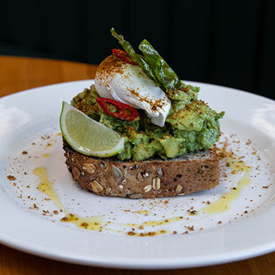 Breakfast of avocado on toast with poached egg and chilli